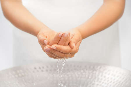 Washing hands above the sink with splashing and dropsの写真素材