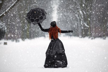 Mysterious red-haired woman in Victorian dress in the winter parkの写真素材