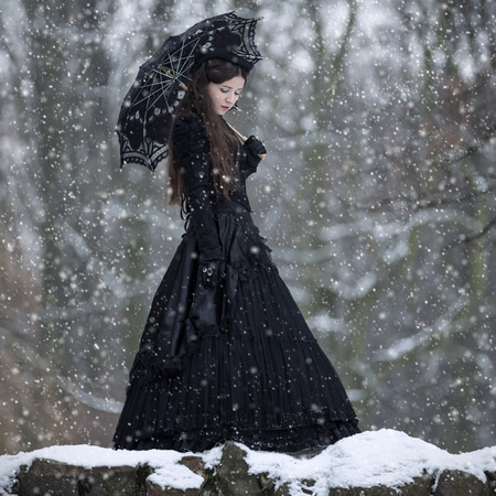 Woman in black Victorian dress in the winter parkの写真素材