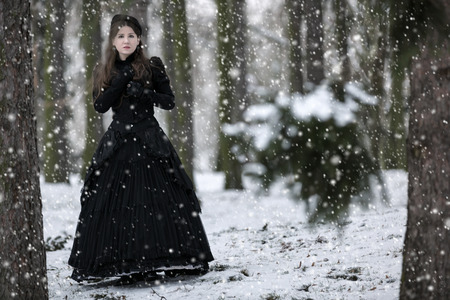 Woman in black Victorian dress in the winter parkの写真素材