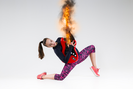 Woman with a burning guitar in the studioの写真素材
