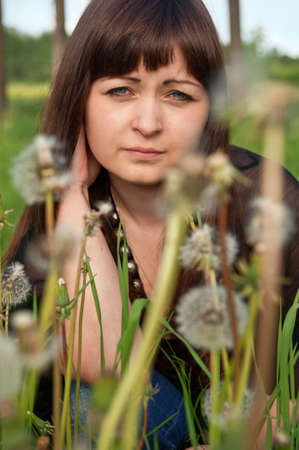 Portrait of young beautiful woman in meadow of dandelions.の写真素材