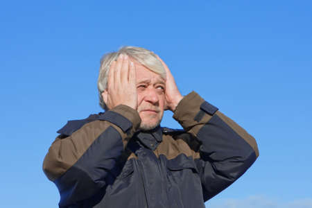 Portrait of mature concerned man with grey hair on blue sky of the background.の写真素材