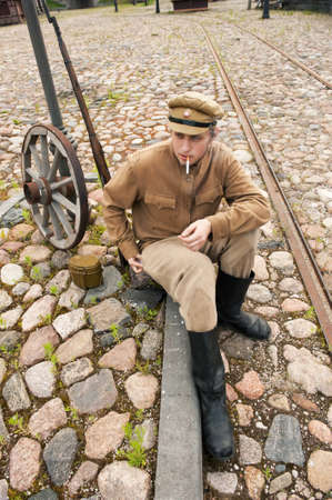 Soldier in uniform of World War I, sit down, resting on the pavement and smoking. Costume accord the times of World War I. Photo made at cinema city Cinevilla in Latvia. の写真素材