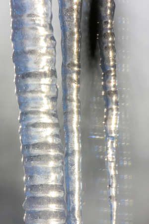 Closeup of  icicles. Icicles hanging from roof. Shiny cold icicles of clear ice hanging in the sunny...