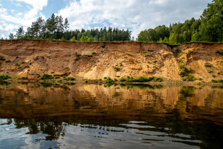 Landscape with cliff near the river Gauja, trees and sky reflection in water. The Gauja is the longest river in Latvia, which is located only in the territory of Latvia.の写真素材