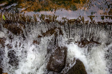 Close up of a fresh clean waterfall in forest, Latvia. Shallow stones stream with running water in spring.の写真素材