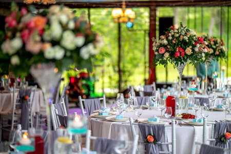 Wedding table decoration. Beautiful bouquet of flowers in vase on the table, next to plates, ...
