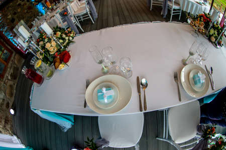 Table setting with handmade gift box on plate, glasses, forks, spoons and knives for wedding...