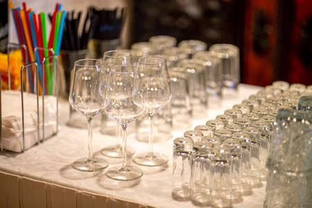 Empty glasses on the white table in restaurant. Lot of crystal glasses arranged on the table for wedding reception.の写真素材