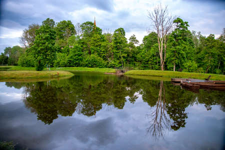 View on summer landscape of pond and trees in sunny day. Reflection of summer trees and clouds in water. Landscape with trees, boat pier and river.の写真素材