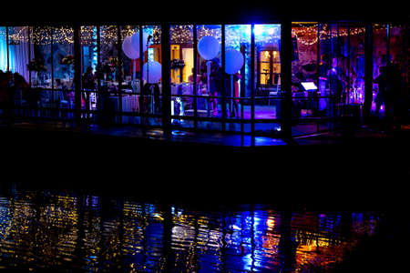 Silhouettes of people in the window during wedding celebrations at night, in the light of colorful...