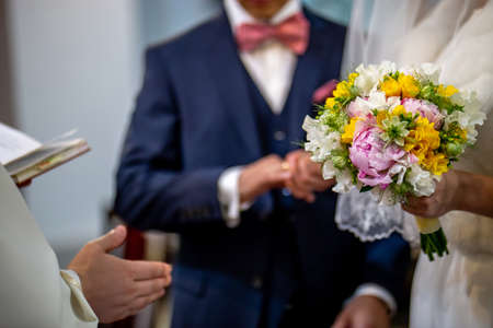 The bride holds a wedding bouquet of beautiful flowers in her hand. The bouquet consists of white,...
