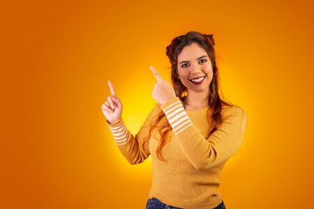 Woman showing information with her hand, with space for text. Yellow backgroundの写真素材