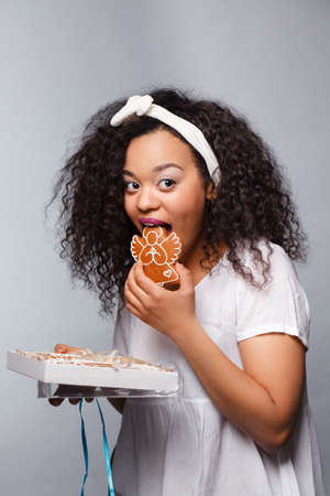 Beautiful happy young woman holding a christmas gift,cookiesの写真素材