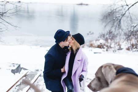 Happy couple walking the dog in a winter landscapeの写真素材