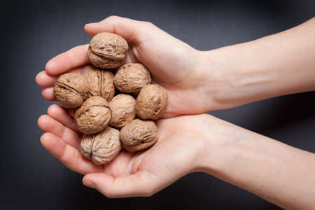 hands holding handful of walnuts over wooden table. view from the topの写真素材
