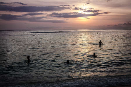 Children swim in the ocean evening sunset at Bali Indonesiaの写真素材