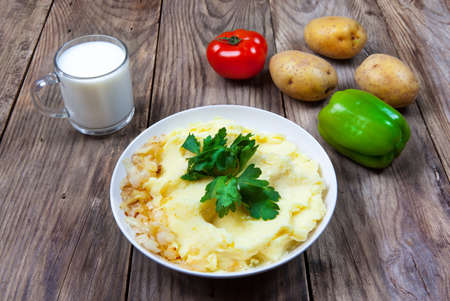 mashed boiled potato with herbs. milk and vegetables on a wooden backgroundの写真素材