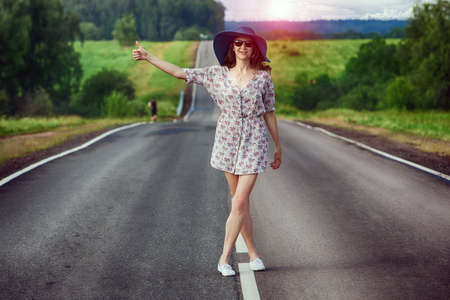 young girl travels on the highway hitchhikingの写真素材