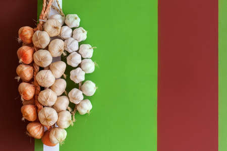 The Onions and garlic in a bundle on bright multi-colored stone wallの写真素材