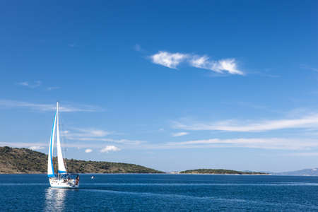 white yacht sailing traveling against a blue sky in a calm seaの写真素材