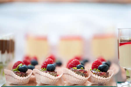 Sweets with raspberries and forest berries on the table with drinks. Design of the holiday. Selective focusの写真素材