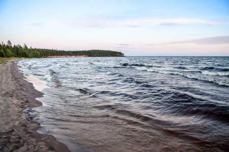 North seascape on Lake Onega - waves beat against the granite shore which reflects the rays of the setting sun.の写真素材