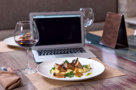 Healthy business lunch in the coffee, top view of vegetable food on white wooden desk near a laptop computer and a glass of red wine. Snack at break timeの写真素材