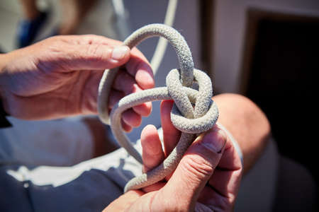 Male hands tying knot on yacht sail boatの写真素材