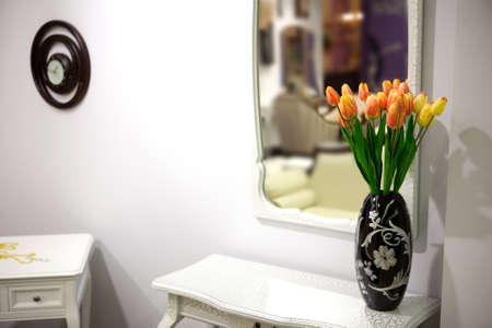 Bouquet of red and yellow tulips in a black vase in a bright room on the dresserの写真素材