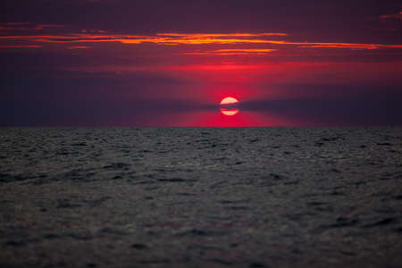 Beautiful red and orange sunset over the sea in a cloudy sky. The sun goes down over the sea. Two seagulls are flying against the sunset. Dramatic Sunset Skyの写真素材