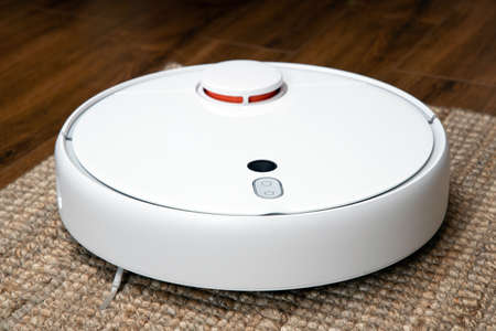 Robotic vacuum cleaner cleans the room from dust and debris, technological progress.の写真素材