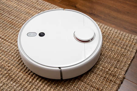 Robotic vacuum cleaner cleans the room from dust and debris, technological progress.の写真素材