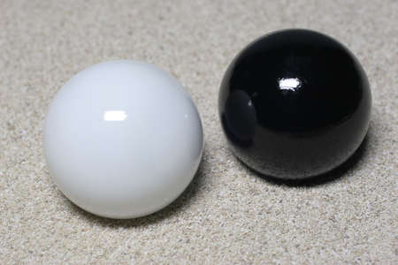 A white and a black ball lay in the sand.の写真素材