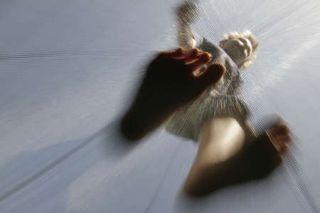 A child jumps on a trampoline up and down.