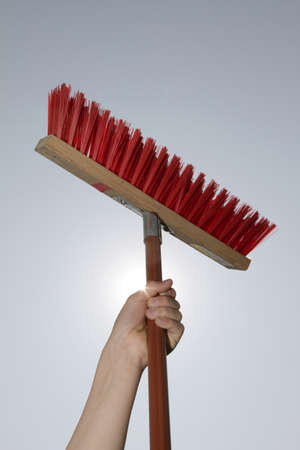 A red broom is held by a child's hand in the sky.の写真素材