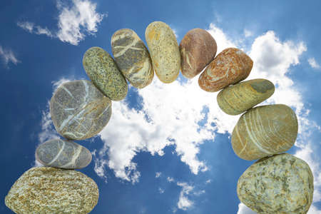 An arch of pebbles in front of a cloudy sky の写真素材