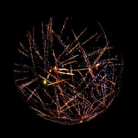 A fireworks display hovers as ball against black background 