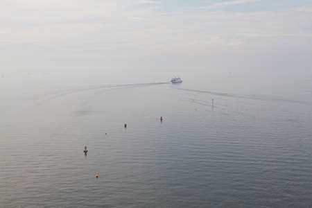 A boat on a lake moves into light fog.の写真素材