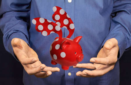 A piggy bank flying flying above two hands.の写真素材