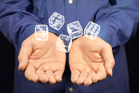 Five white dices hovering above two hands.の写真素材