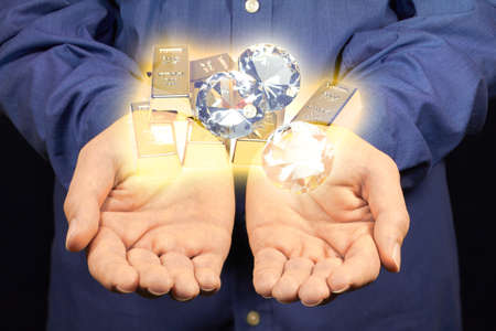 Gold and diamonds hovering above two hands.の写真素材