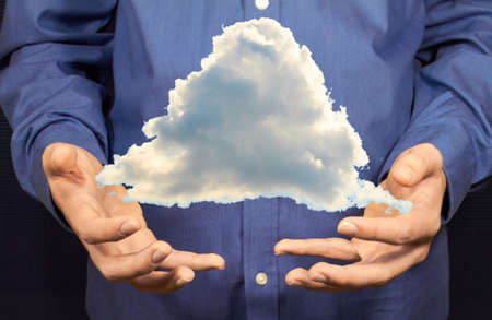 A triangular cloud flying above two hands.の写真素材