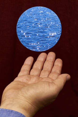 A ball of water floating above a hand.の写真素材