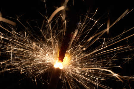 Burning sparkler in front of a dark background.の写真素材