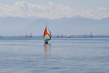 A sailboat with colorful sails moves over Lake Constance.の写真素材
