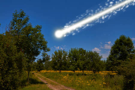 A large bright meteorite is dragging a long trail of light across the sky.の写真素材