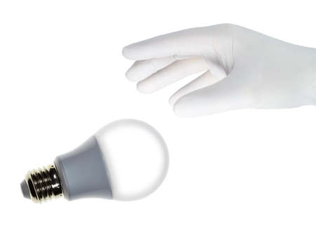 A hand in a white glove grabs a led lamp.の写真素材