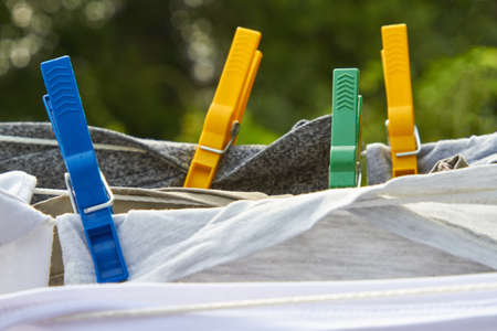 Garments hang dry on a clothesline and are held in place by clothespins.